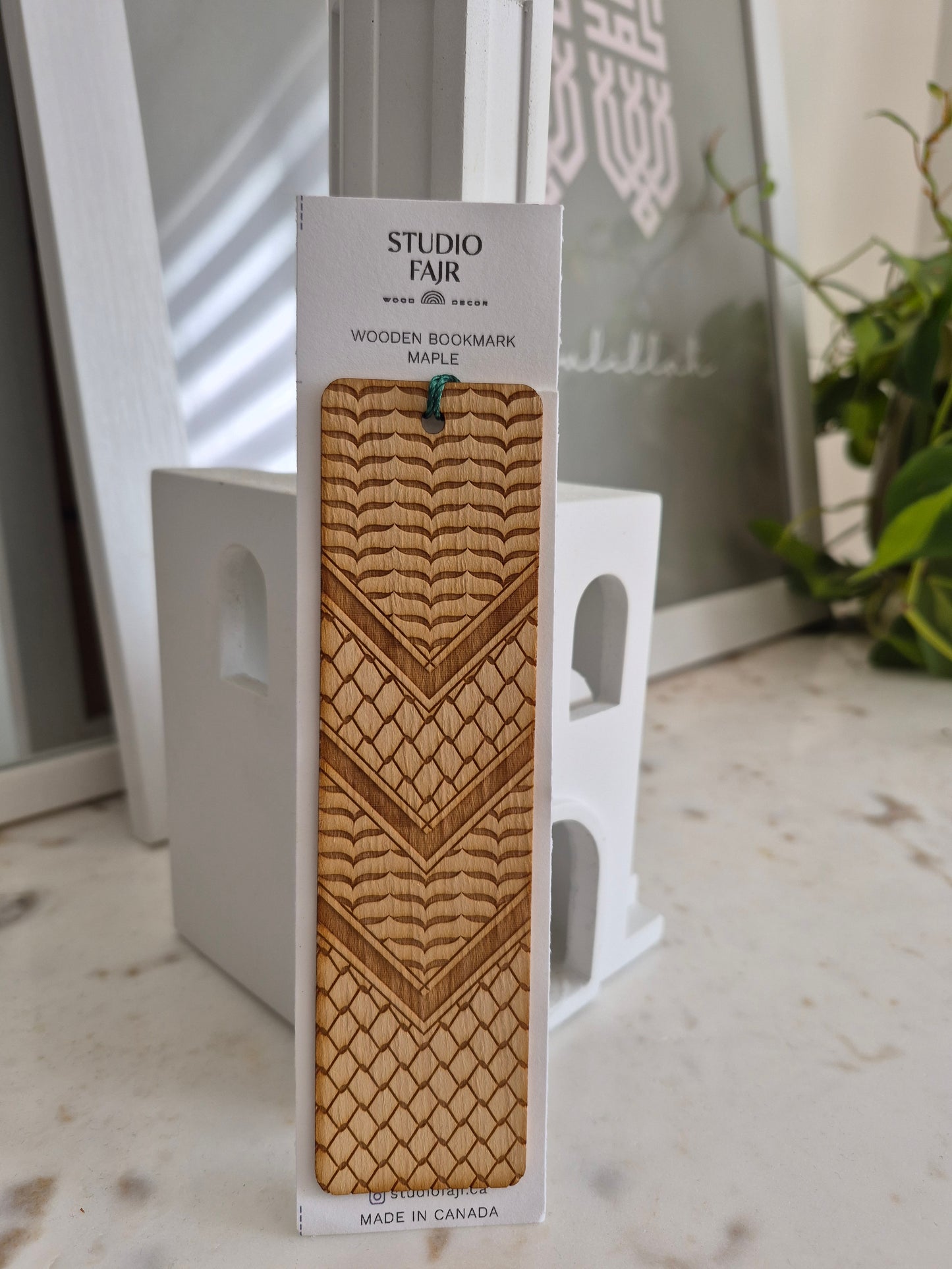 Kufiya Wooden bookmark with pattern on a white card labeled 'Studio Fair' against a blurred background.